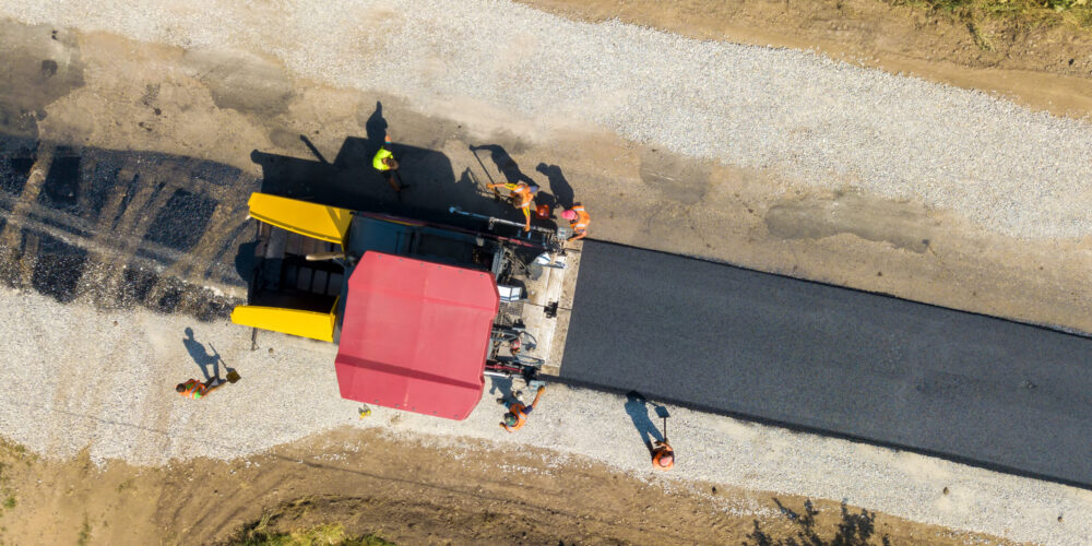 Aerial view of new road construction with asphalt laying machinery at work.