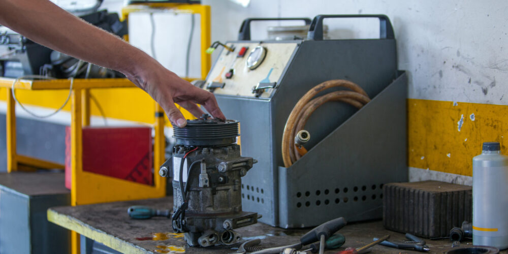 A caucasian male holding a damaged part of a car next to his working tools