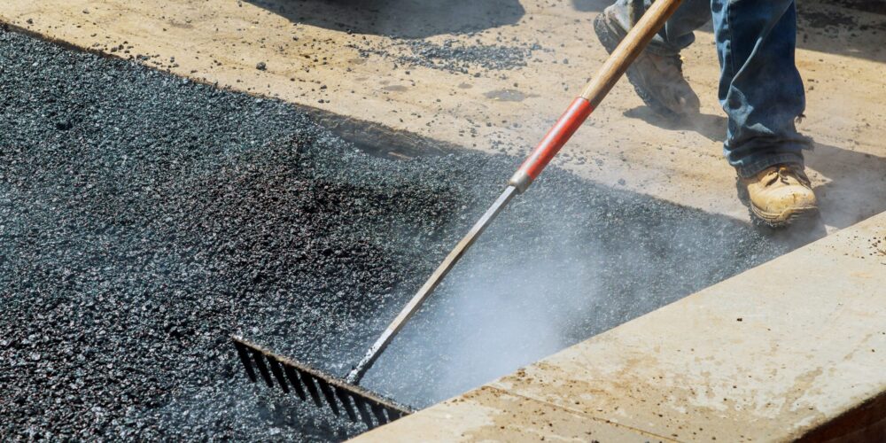 Workers on Asphalting paver during Road street repairing works. Street resurfacing. Fresh asphalt construction. Bad road