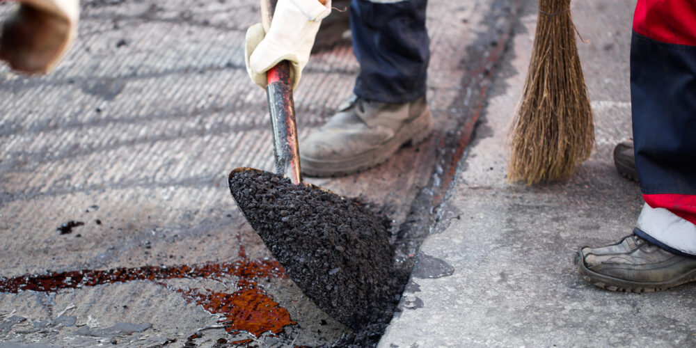 Young builder on Asphalting paver machine during Road street repairing works